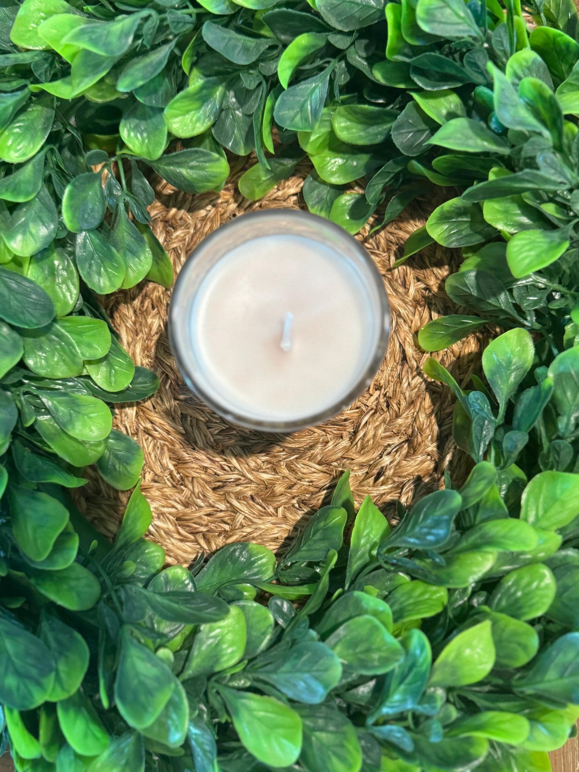a close up of a candle surrounded by green leaves