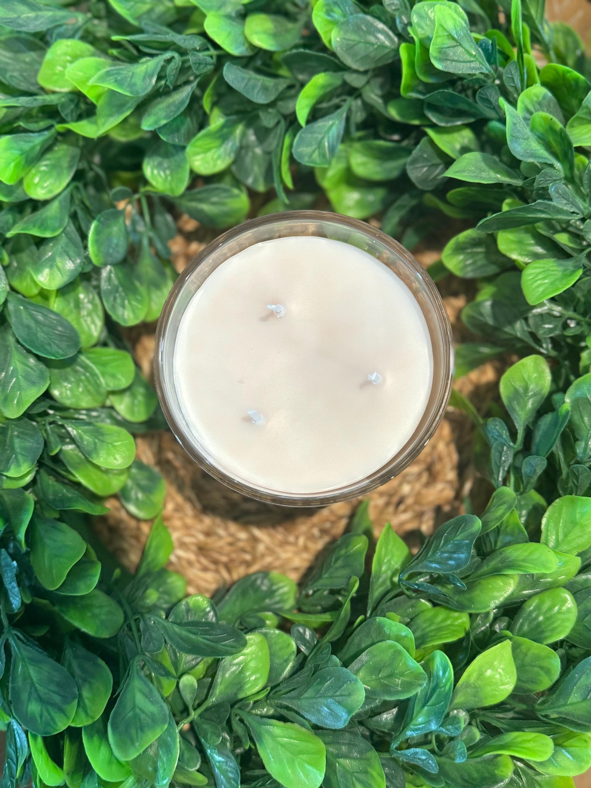 a candle surrounded by green leaves